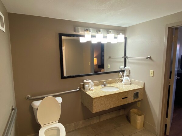 A bathroom with a toilet, sink, mirror, and towel rack. - Red Roof Inn Savannah North I-95 – Port Wentworth (Port Wentworth)