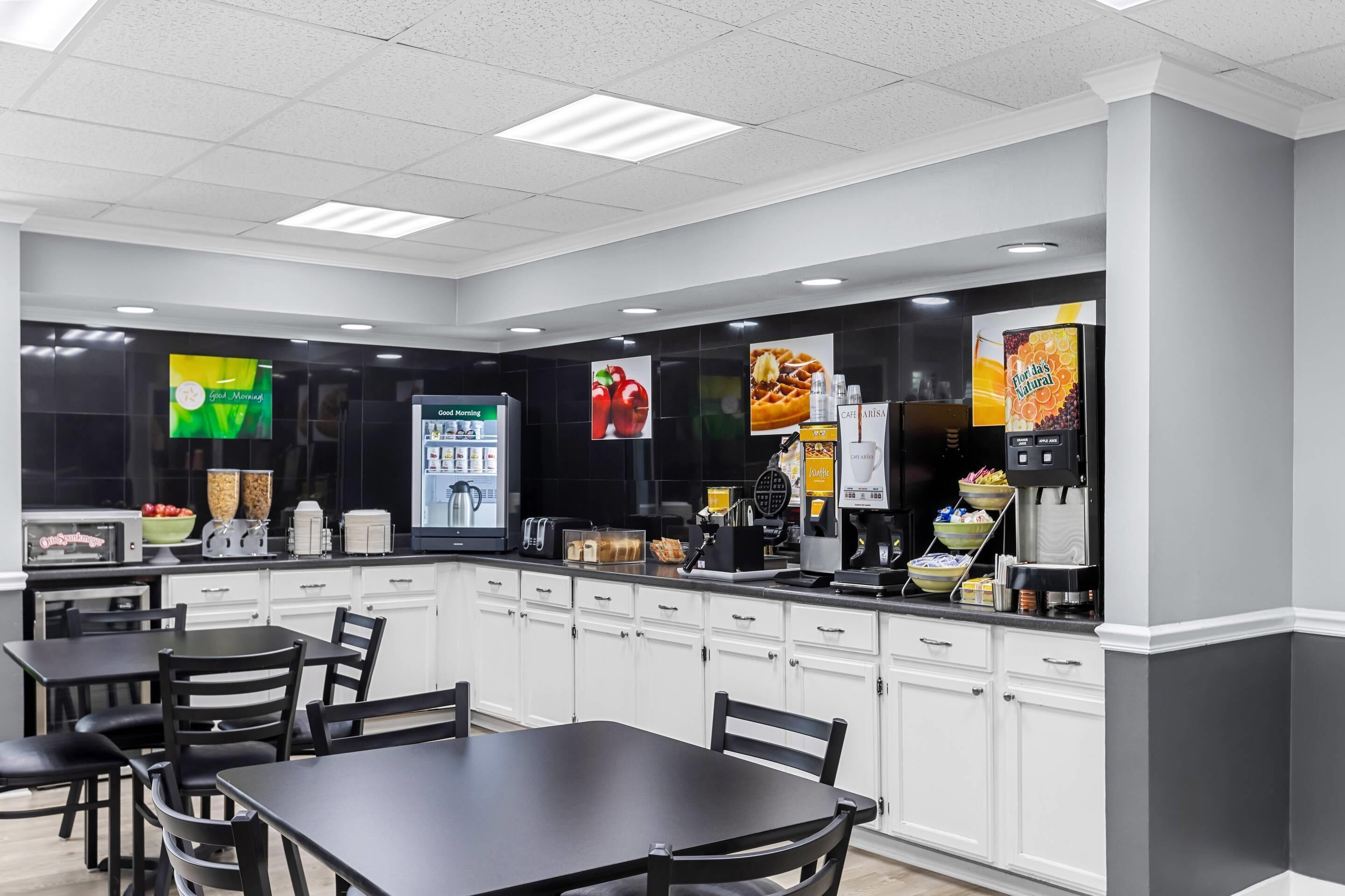 Un café moderno con mostrador, zona de estar y varios dispensadores de comida y bebida.