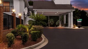 Un hotel moderno con entrada cubierta, antena parabólica y jardines bien cuidados.