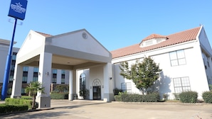 A hotel entrance with a covered walkway, a sign for Ameris Best Value Inn, and a clear blue sky.