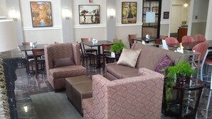 A hotel lobby with seating areas, a reception desk, and artwork on the walls. - Americas Best Value Inn Monroe (Monroe)