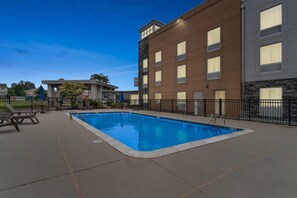 A swimming pool with a surrounding deck, a fence, and a building with a sign that reads "Comfort Suites." - Comfort Inn Rehoboth Beach (Rehoboth Beach)