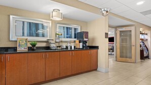 A modern kitchen area with wooden cabinets, a black countertop, and a large window. - Comfort Inn Rehoboth Beach (Rehoboth Beach)