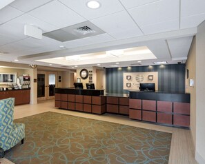 A hotel reception area with a reception desk, a clock, and a wall-mounted sign. - Comfort Inn Rehoboth Beach (Rehoboth Beach)