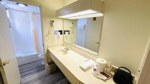 A bathroom with a sink, mirror, and shower. - Relax Inn Perry (Perry)