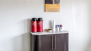 A kitchenette with two Folgers coffee makers, a basket of coffee pods, and a Nespresso machine.