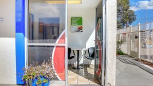 A blue and white building with a 'welcome' sign, a glass door, and a table with chairs inside. - Motel 6 Santa Fe (Santa Fe)