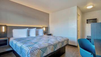 A modern hotel room with a large bed, bedside tables, a desk, and a chair.