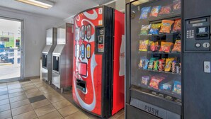 A vending machine with a Coca-Cola design, a push button, and a variety of snacks. - Motel 6 Santa Fe (Santa Fe)