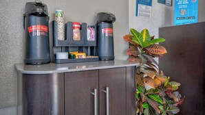 A coffee station with branded dispensers, a small refrigerator, and a plant. - Motel 6 Santa Fe (Santa Fe)