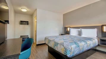Una habitación de hotel con una cama, un escritorio, una silla y un televisor.