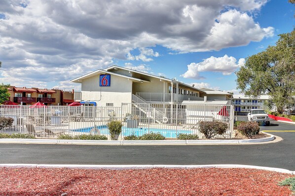 A hotel with a swimming pool, fenced area, and a parking lot.
