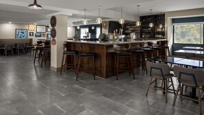 A modern bar area with a central island, bar stools, and a seating area with tables and chairs.