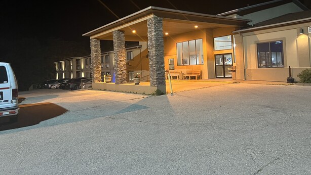 A two-story building with a covered outdoor seating area, stone pillars, and a parking lot at night. - Days Inn by Wyndham Boonville (Boonville)