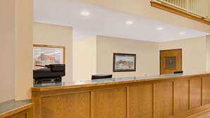 A reception desk with framed pictures on the wall, a wooden counter, and a door with a sign. - Days Inn by Wyndham Boonville (Boonville)