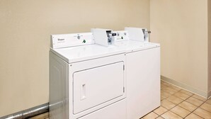 A white Whirlpool washer and dryer unit in a corner with a tiled floor. - Days Inn by Wyndham Boonville (Boonville)