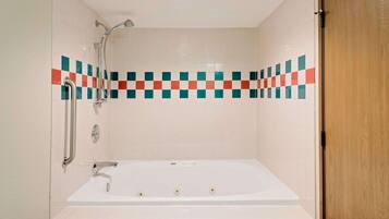 A bathroom with a bathtub, a shower, and a handrail.