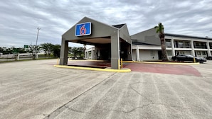 A motel with a '6' sign, a covered parking area, and a building with multiple floors. - Motel 6 Lake Charles, LA (Lake Charles)