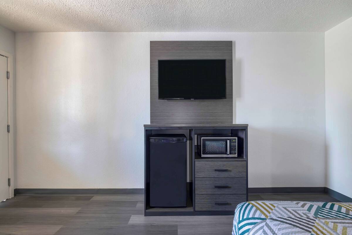 A compact room with a built-in TV, a microwave, and a small refrigerator.