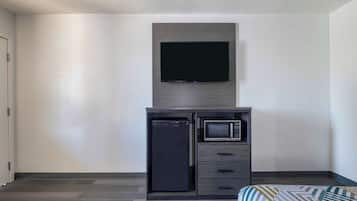 Een kleine kamer met een ingebouwde televisie, een magnetron en een kleine koelkast.