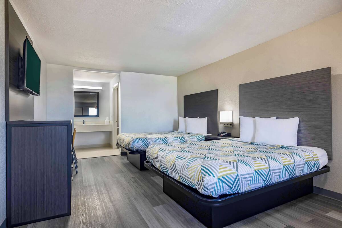 A hotel room with a large bed, bedside tables, a flat-screen TV, and a desk with a chair.