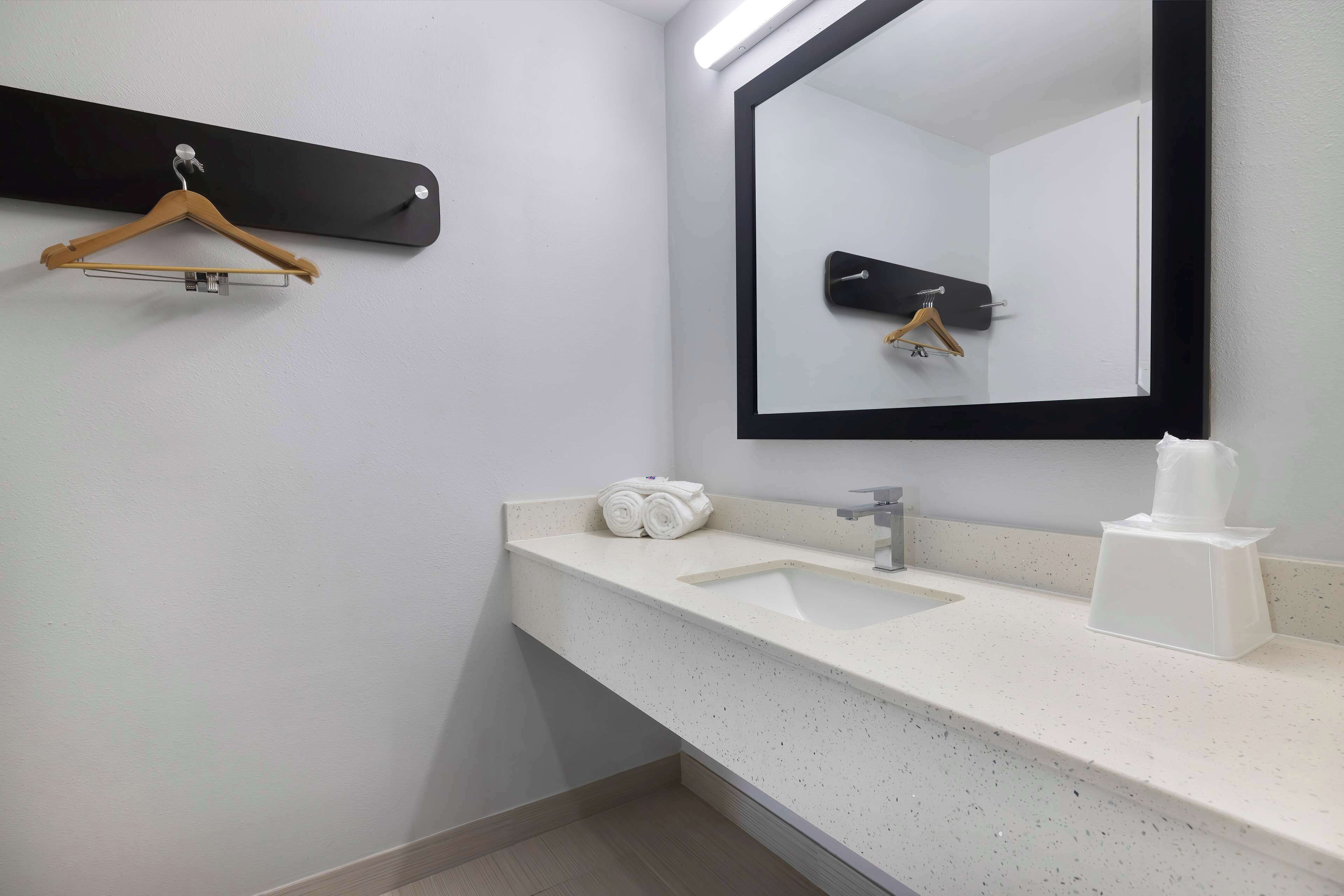 Une salle de bain avec un lavabo blanc, un miroir et un porte-serviettes.