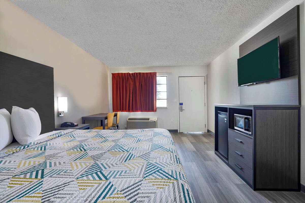A hotel room with a bed, a desk, a TV, a microwave, and a wardrobe.