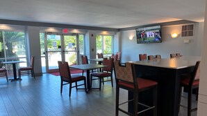 A restaurant with tables and chairs, a TV screen, and large windows. - Ramada by Wyndham Luling (Luling)