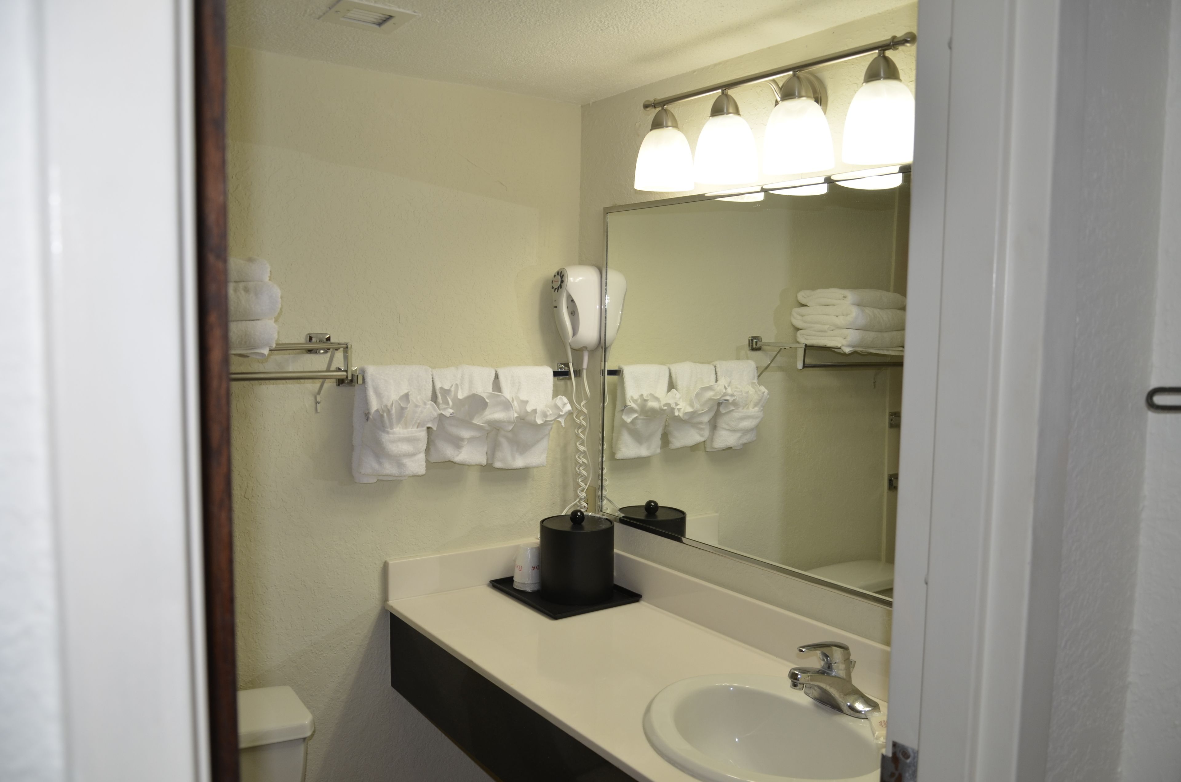 A bathroom with a sink, mirror, towel rack, and hair dryer.