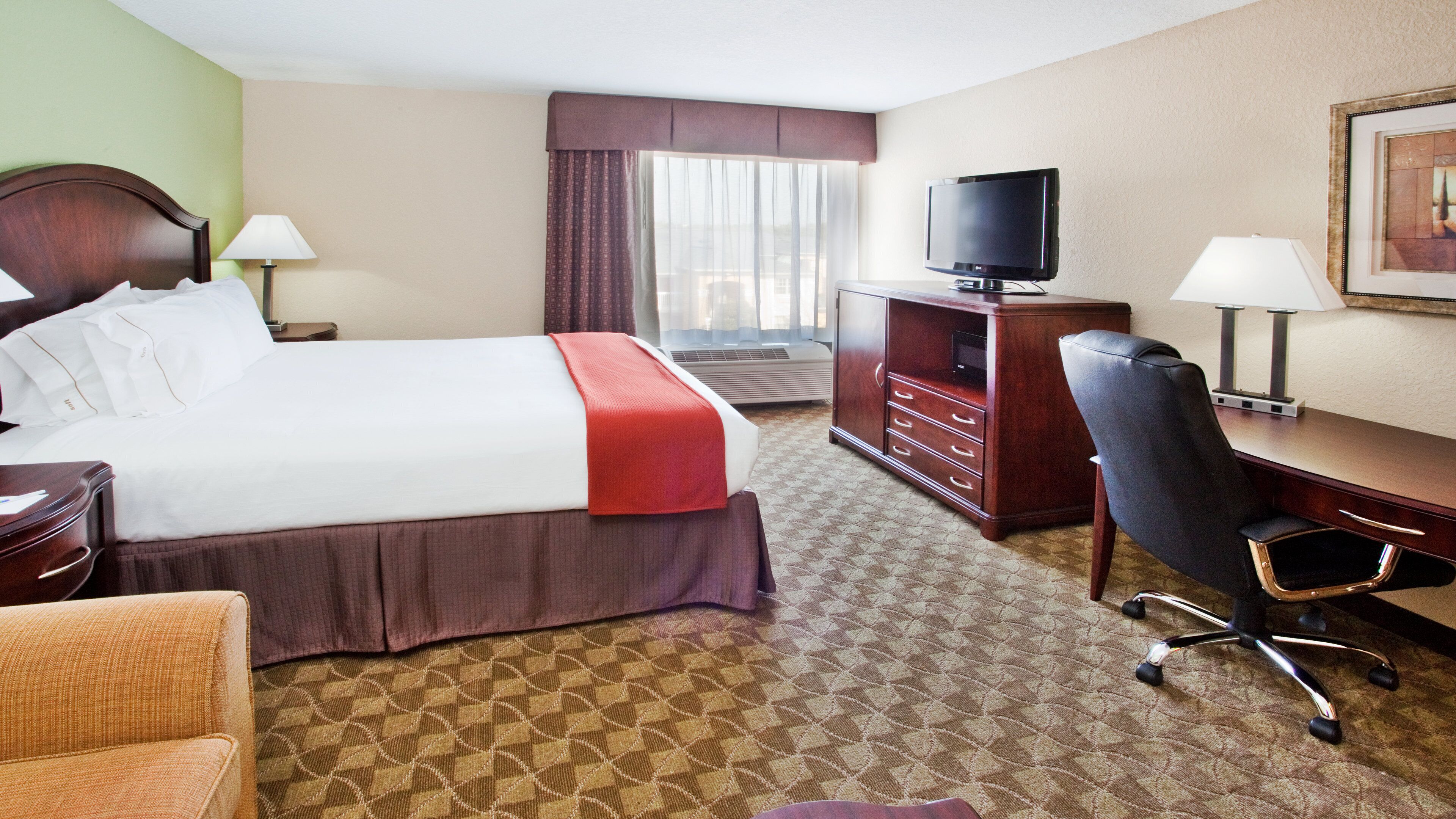 Une chambre d’hôtel comprenant un lit, un bureau, une chaise, une télévision et une commode.