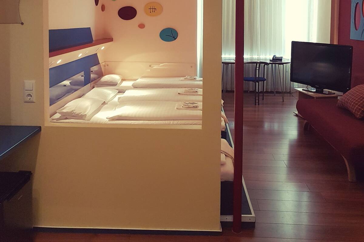 Una habitación con una cama, un televisor y un sofá rojo.