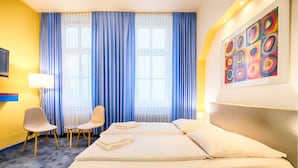 Una habitación de hotel con dos camas, televisión, escritorio y silla.
