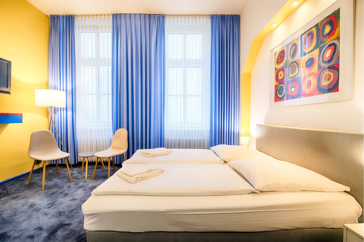 Una habitación de hotel con dos camas, televisión, escritorio y silla.
