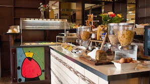 Mostrador de buffet con diferentes opciones de comida, entre ellas tazones de cereales, frutas y un pastel.