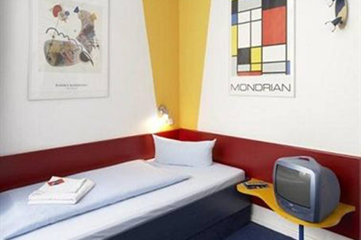 Una habitación con una cama, televisión y obras de arte en las paredes.