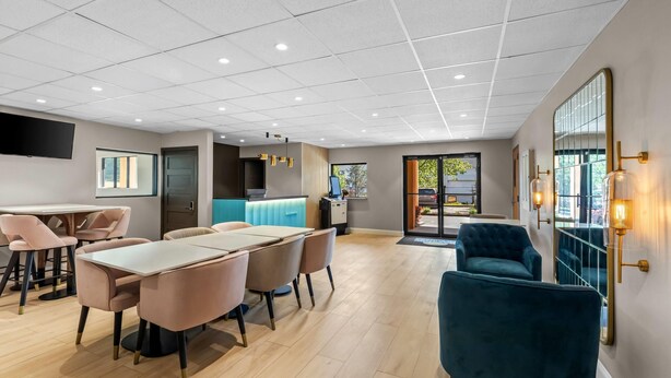 A modern hotel lobby with a reception desk, seating area, and large windows. - Days Inn & Suites by Wyndham Peachtree Corners/Norcross (Peachtree Corners)