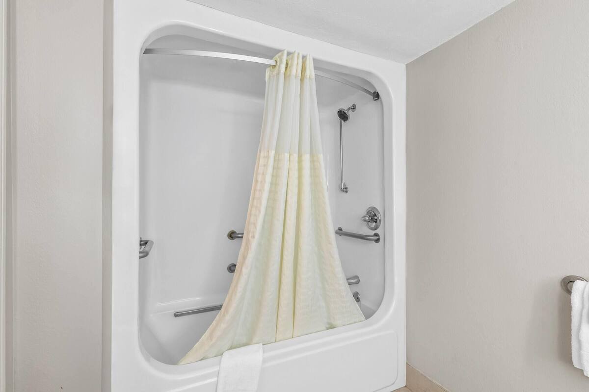 Una bañera con cabezal de ducha, toallero y cortina.