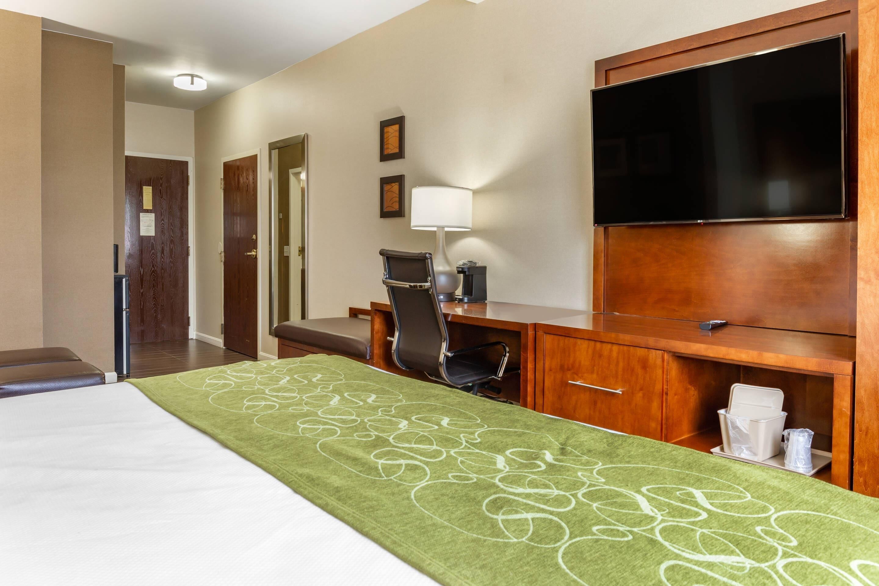 A hotel room with a bed, a desk, a chair, a television, and a bathroom.