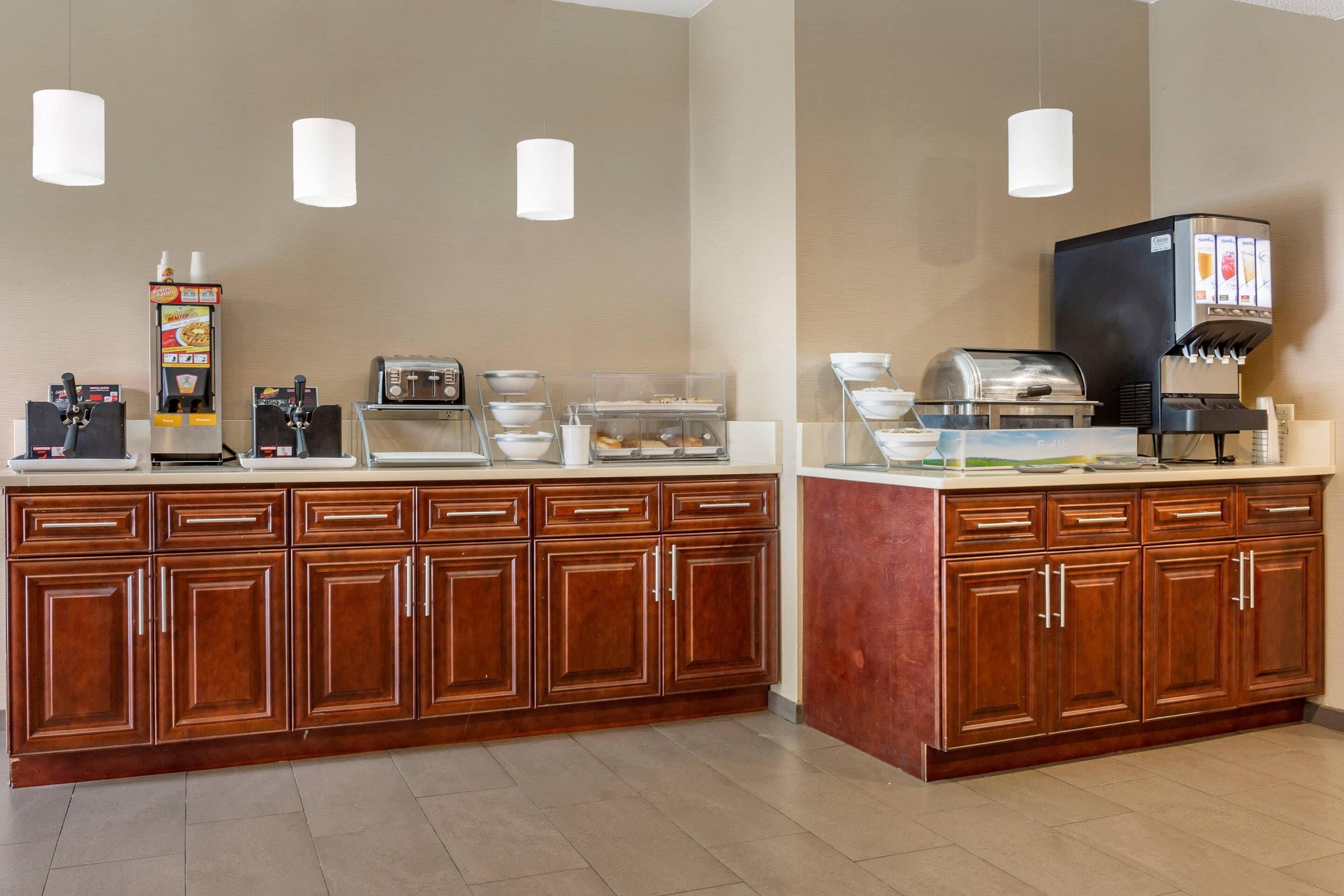A hotel breakfast area with a coffee machine, toaster, and beverage dispenser.