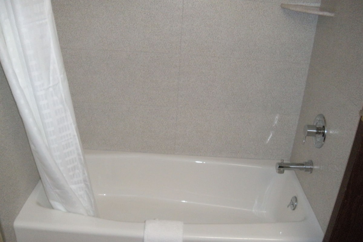 A standard white bathtub with a shower curtain, a towel rack, and a faucet.