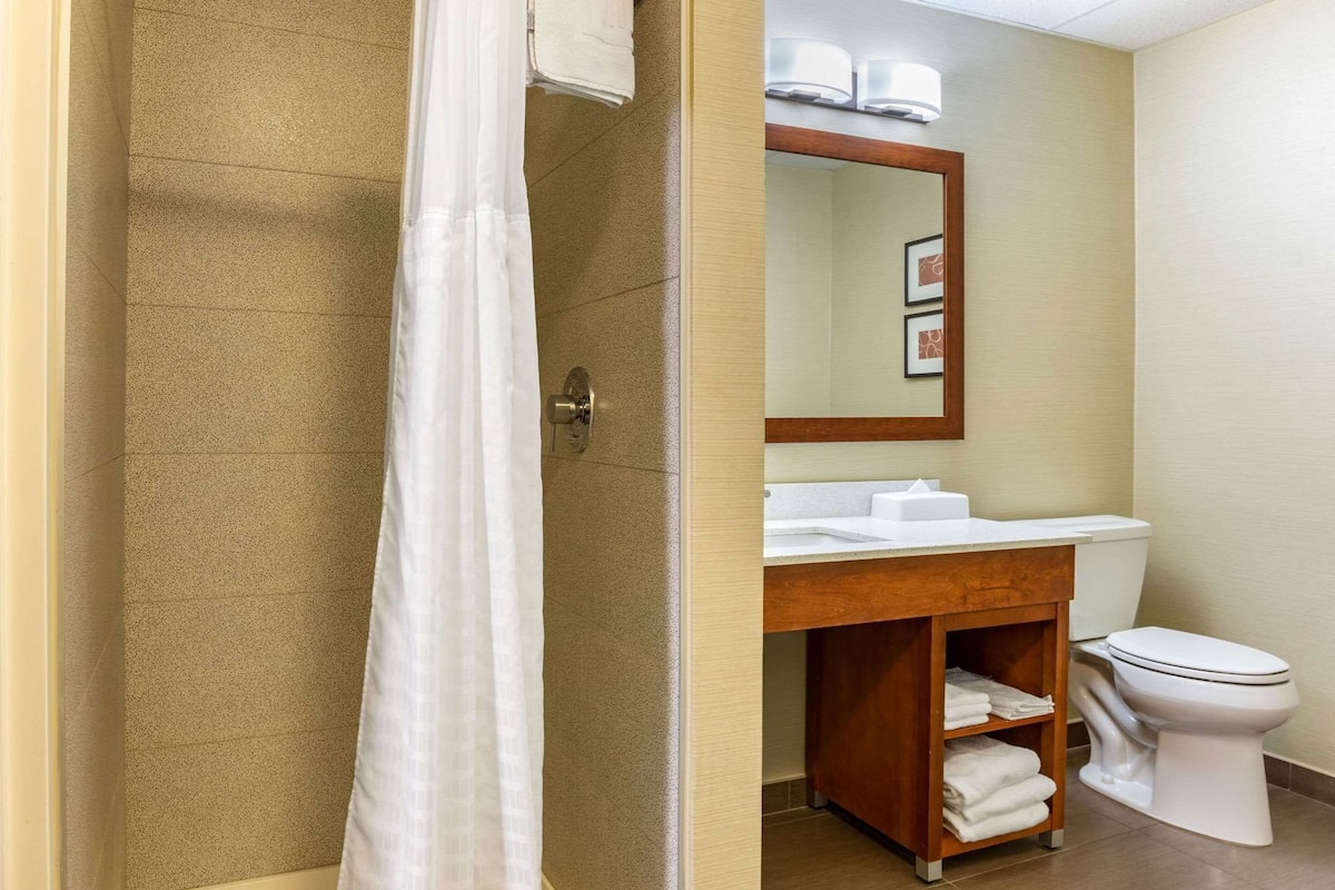 A bathroom with a shower curtain, a sink, a mirror, and a toilet.