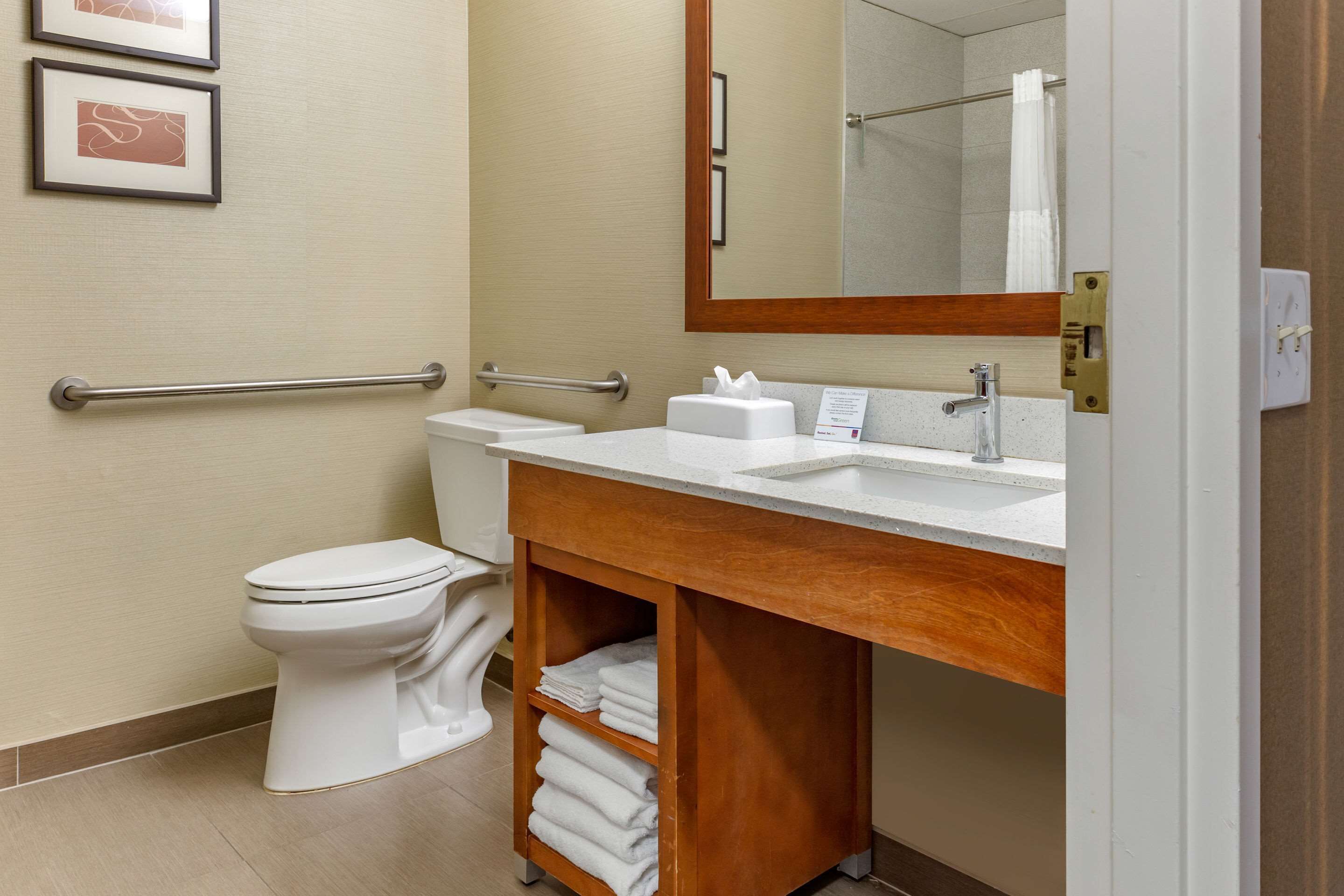 Een moderne badkamer met een wit toilet, een wastafel met spiegel en een handdoekrek.