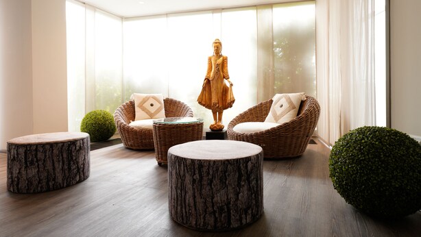 Un interior moderno con muebles de mimbre, taburetes redondos y una estatua.
