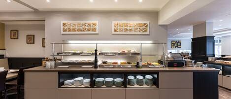 A modern buffet setup with multiple food stations, a self-service beverage dispenser, and neatly arranged plates.