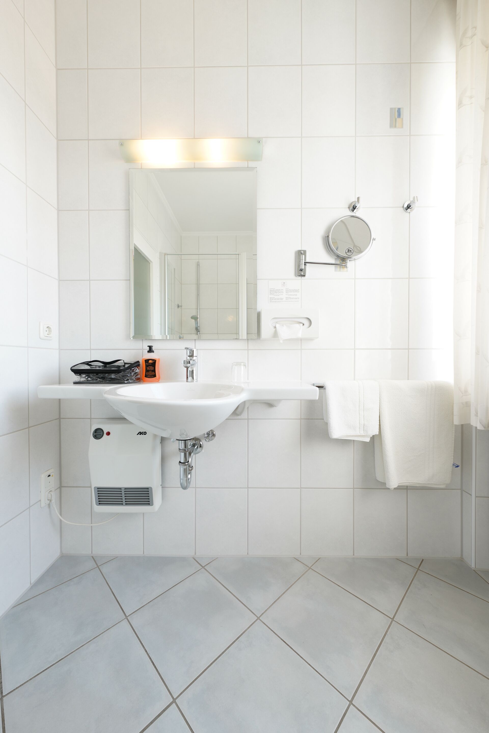 A modern bathroom with a white sink, mirror, and towel rack.