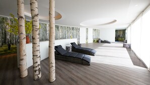 Un espacio interior moderno con columnas de abedul, suelo de madera oscura y un amplio ventanal que proporciona luz natural.