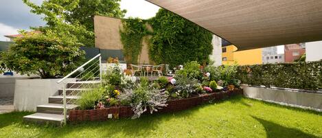 A garden area with a staircase, a seating area with chairs, and a variety of plants and flowers.