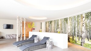 Un moderno espacio de spa con un gran mural en la pared, un mostrador de recepción y dos sillones de descanso.