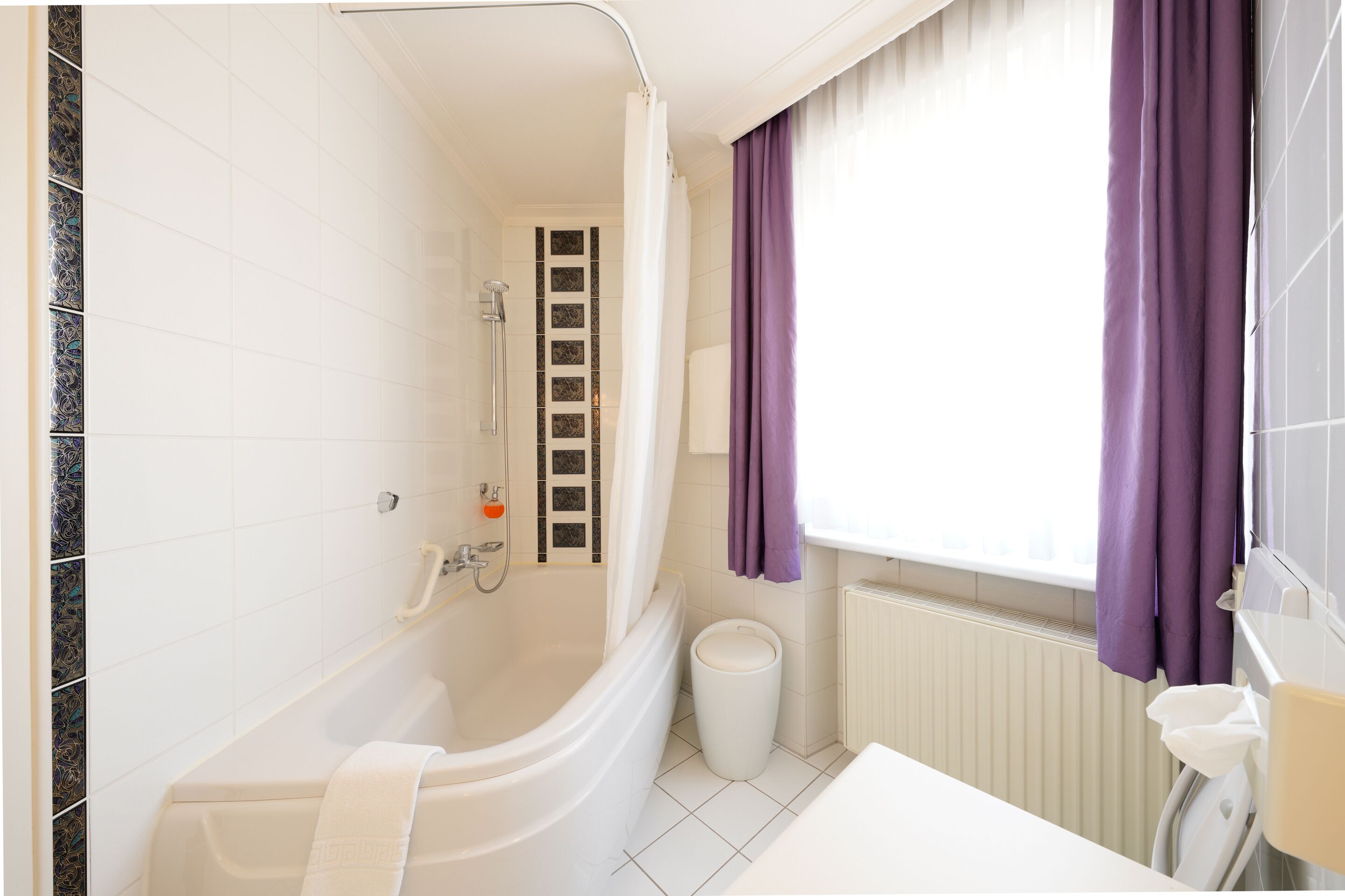 A modern bathroom with a bathtub, shower, and toilet.