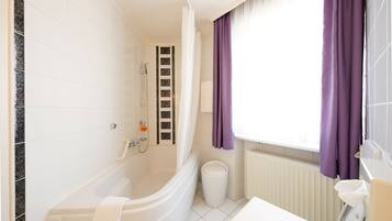 A modern bathroom with a bathtub, shower, and toilet.